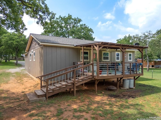 back of house with a deck, a yard, board and batten siding, and roof with shingles