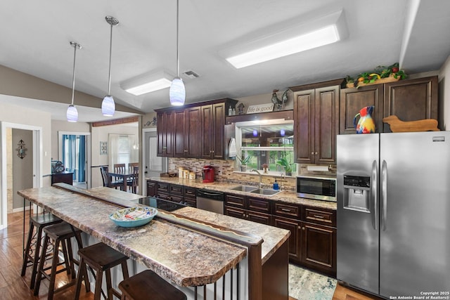 kitchen featuring decorative backsplash, a sink, a breakfast bar, stainless steel appliances, and a center island