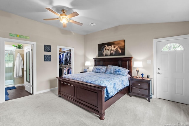 bedroom featuring baseboards, light colored carpet, a closet, a walk in closet, and visible vents