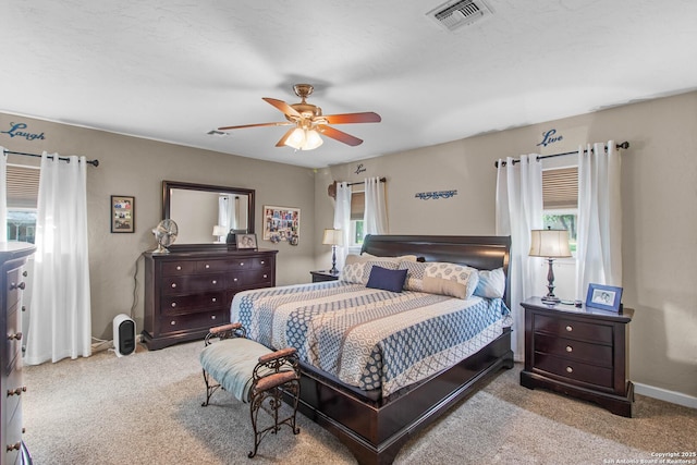 carpeted bedroom with visible vents, a ceiling fan, and baseboards