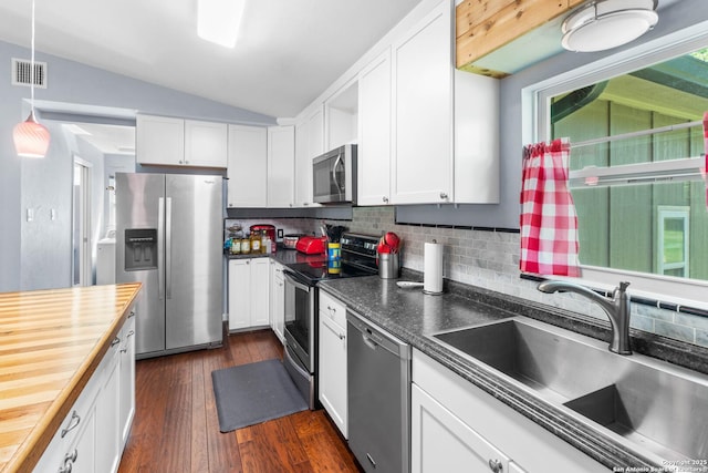 kitchen featuring tasteful backsplash, stainless steel appliances, vaulted ceiling, a sink, and visible vents