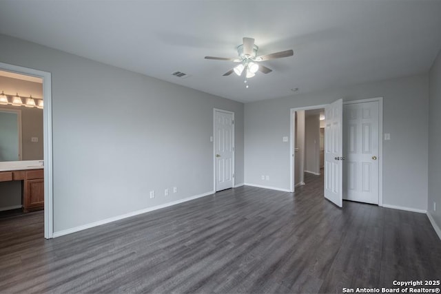 unfurnished bedroom featuring dark wood-style flooring, connected bathroom, a ceiling fan, visible vents, and baseboards