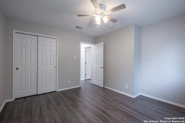 unfurnished bedroom featuring visible vents, a closet, dark wood finished floors, and baseboards