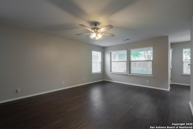 unfurnished room with ceiling fan, visible vents, dark wood-style floors, and baseboards