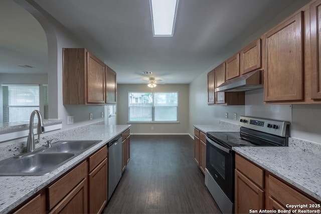 kitchen featuring stainless steel appliances, under cabinet range hood, a sink, baseboards, and dark wood-type flooring