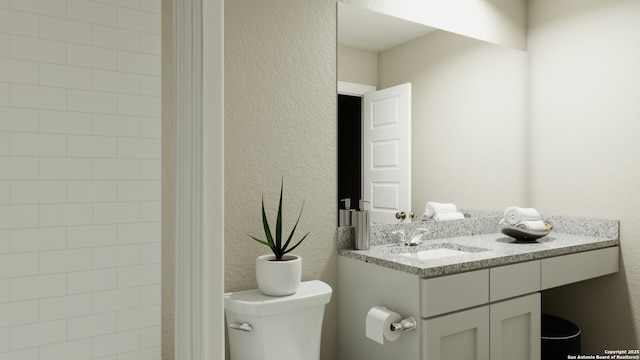 bathroom with toilet, a textured wall, and vanity
