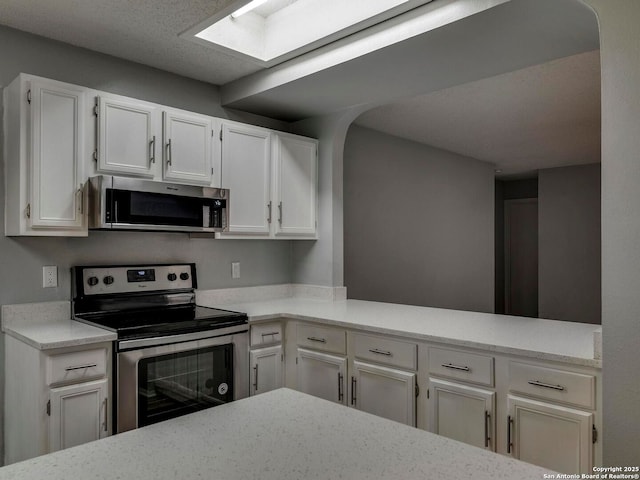 kitchen featuring white cabinetry, stainless steel appliances, light countertops, and a skylight