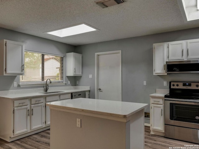 kitchen with a sink, visible vents, stainless steel appliances, wood finished floors, and a skylight