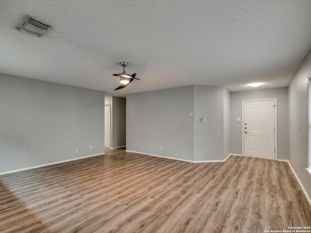 unfurnished living room with a textured ceiling, visible vents, and light wood-style floors