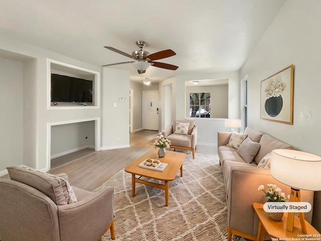 living area with a ceiling fan, baseboards, and light wood-style floors