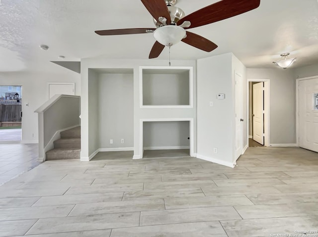 unfurnished living room featuring ceiling fan, baseboards, and stairs
