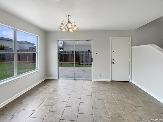 unfurnished dining area with a chandelier, baseboards, light tile patterned floors, and a wealth of natural light