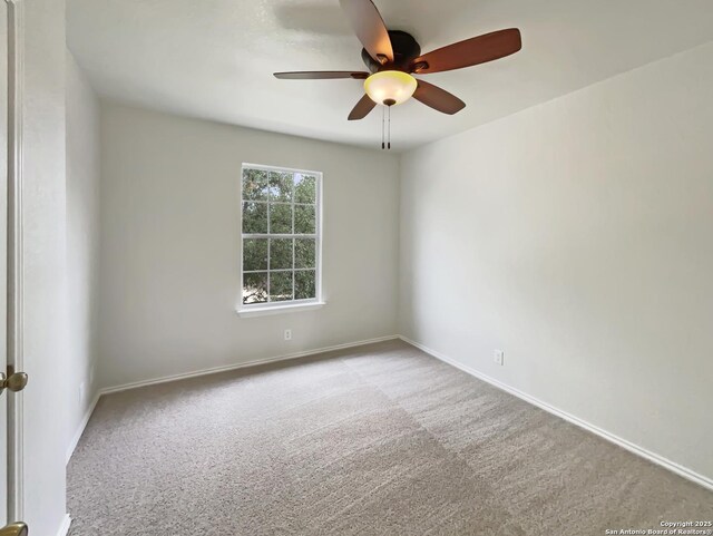 carpeted empty room featuring baseboards and a ceiling fan