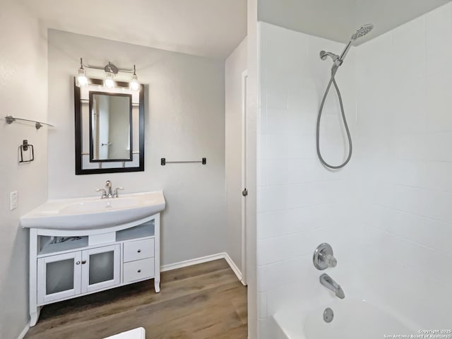 full bath featuring baseboards, wood finished floors, shower / tub combination, and vanity