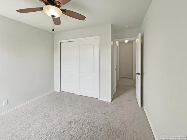 unfurnished bedroom with light colored carpet, baseboards, a ceiling fan, and a closet