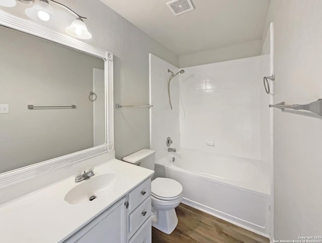 bathroom featuring vanity, toilet, visible vents, bathtub / shower combination, and wood finished floors