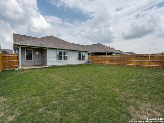 rear view of house featuring cooling unit, a patio, a shingled roof, a yard, and a fenced backyard