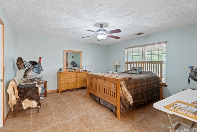 bedroom featuring a textured ceiling, visible vents, and a ceiling fan
