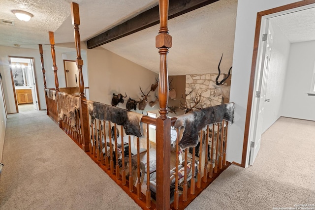 corridor featuring lofted ceiling with beams, a textured ceiling, visible vents, and carpet floors