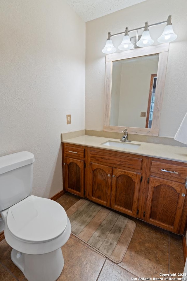bathroom with tile patterned flooring, toilet, a textured ceiling, and vanity