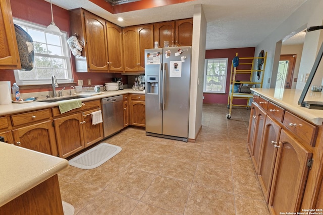 kitchen with brown cabinets, a sink, appliances with stainless steel finishes, and light countertops