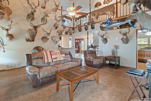 living room featuring tile patterned flooring, a ceiling fan, visible vents, and baseboards