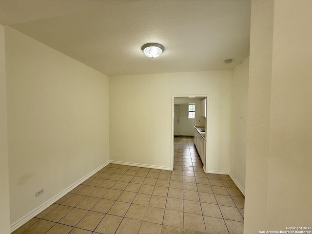 empty room featuring light tile patterned flooring and baseboards