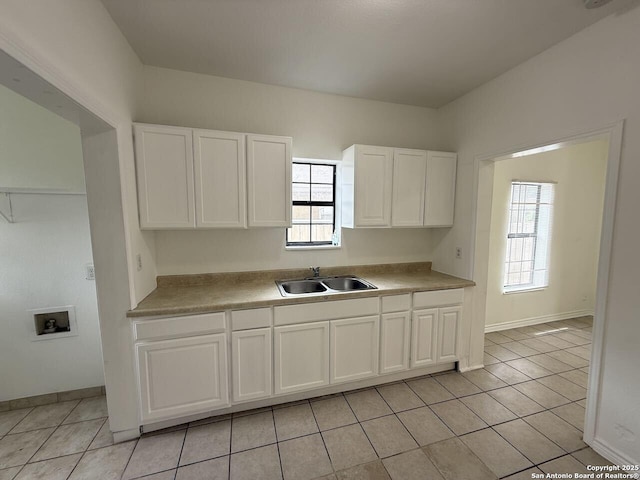 kitchen featuring light tile patterned floors, a sink, a wealth of natural light, and white cabinetry