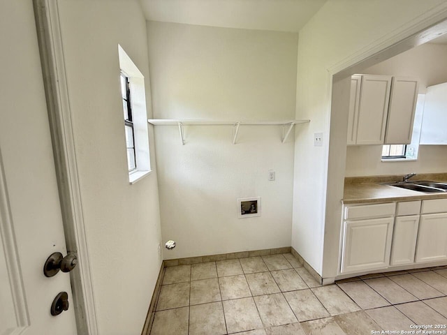 washroom featuring baseboards, washer hookup, cabinet space, and a sink