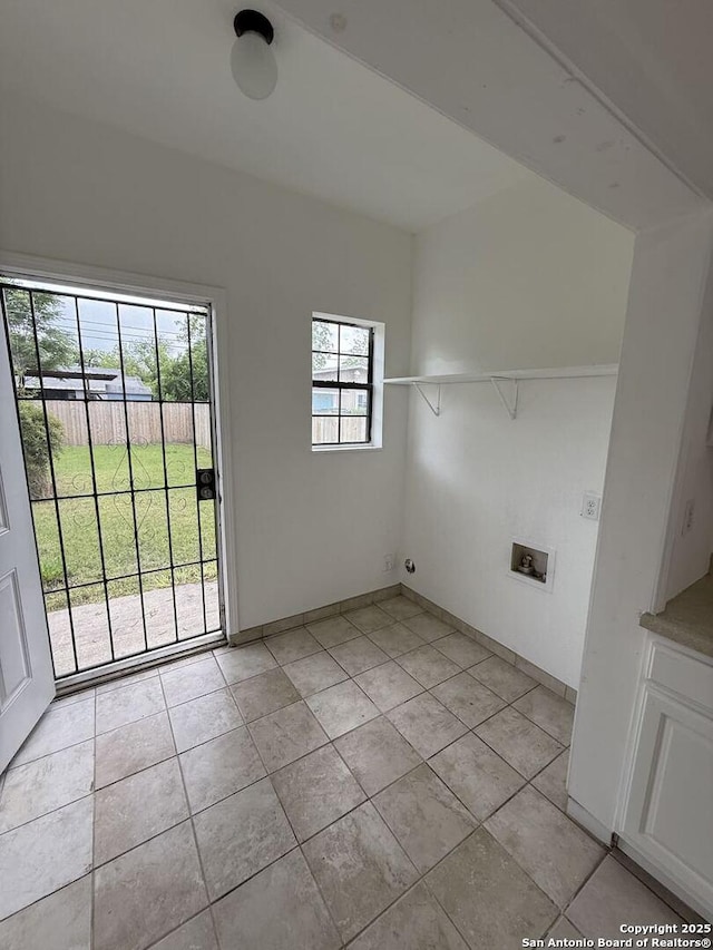 interior space featuring baseboards, hookup for a washing machine, light tile patterned flooring, and laundry area