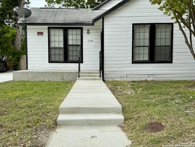 view of front of house with a front yard and roof with shingles