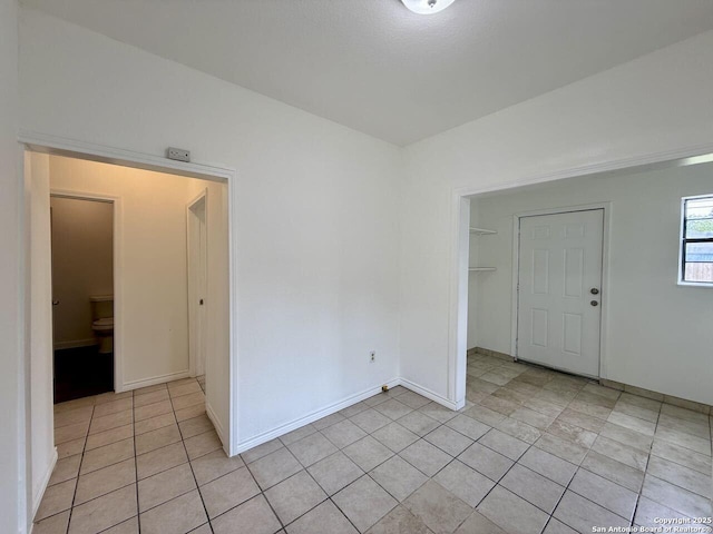 spare room featuring light tile patterned floors and baseboards