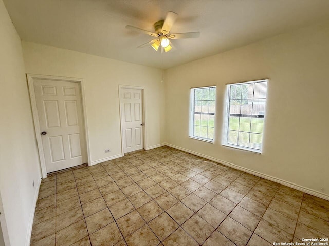 empty room with light tile patterned floors, ceiling fan, and baseboards