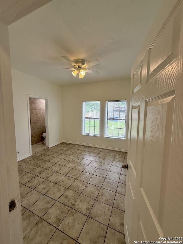 unfurnished room with light tile patterned flooring, a ceiling fan, and baseboards
