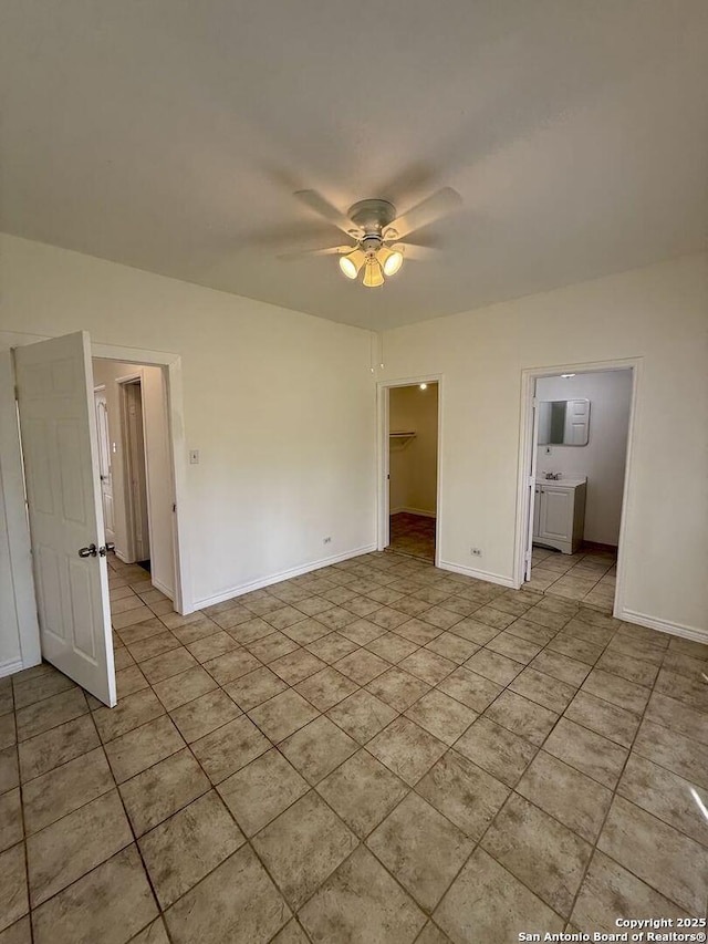 unfurnished bedroom featuring light tile patterned flooring, ensuite bath, baseboards, and a spacious closet