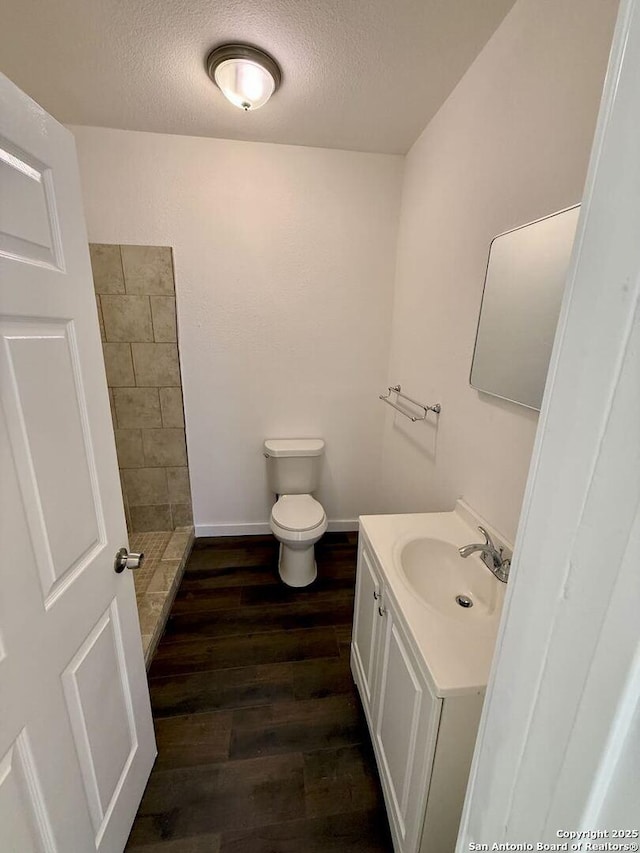 bathroom featuring toilet, vanity, a textured ceiling, and wood finished floors