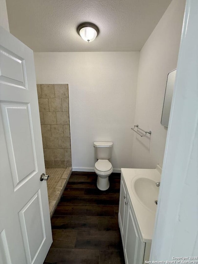 bathroom featuring a tile shower, a textured ceiling, wood finished floors, and vanity