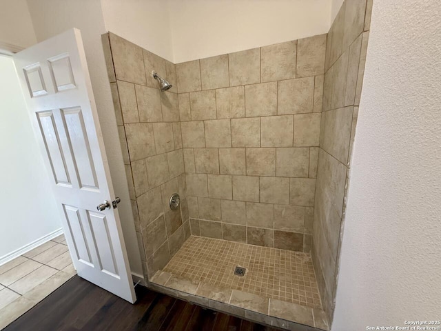 full bath featuring a tile shower and wood finished floors