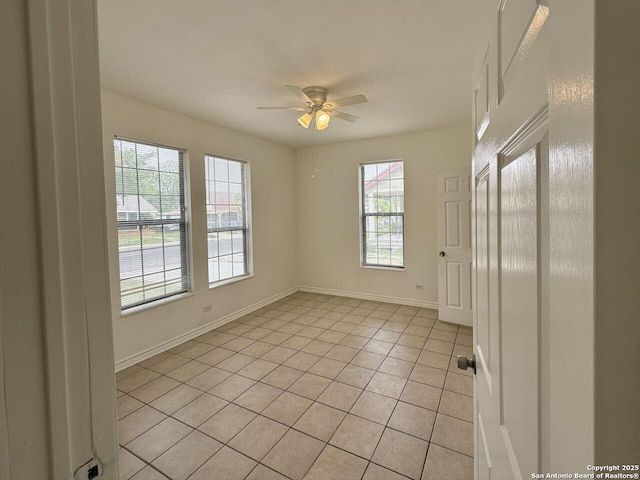 unfurnished room with baseboards, light tile patterned floors, and a ceiling fan