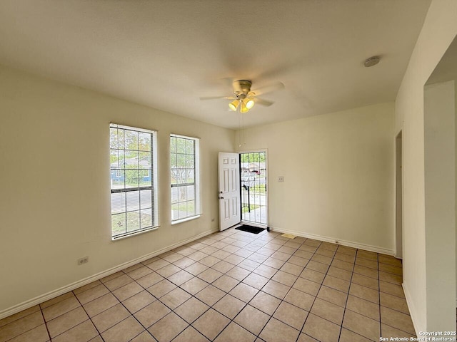 spare room featuring light tile patterned floors, ceiling fan, and baseboards