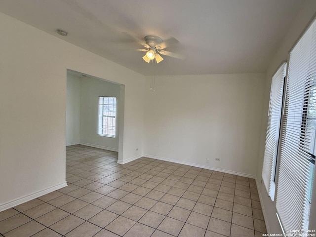 empty room featuring light tile patterned flooring, ceiling fan, and baseboards