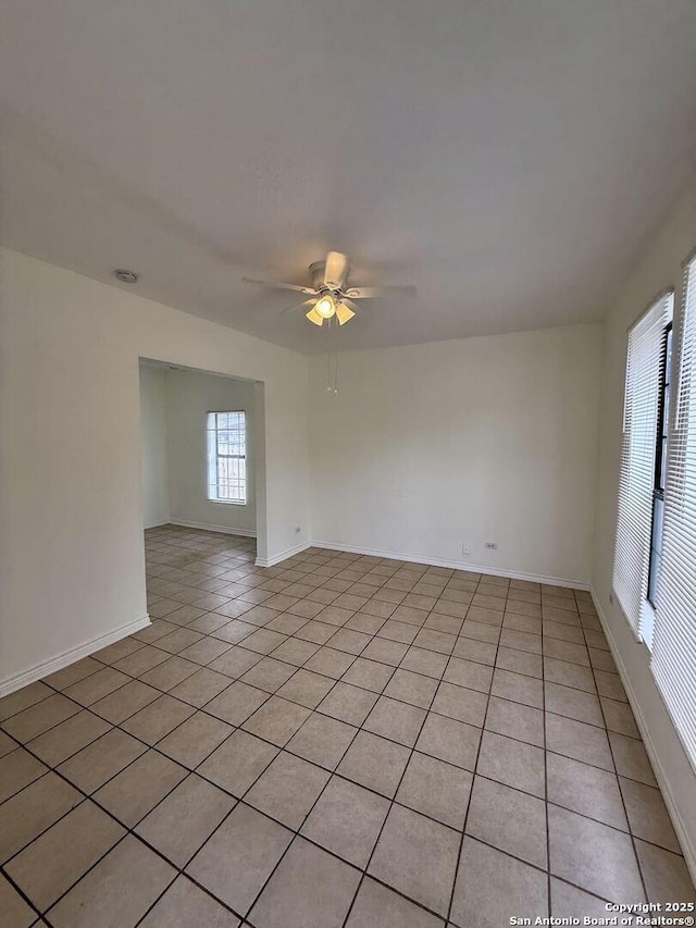 spare room featuring baseboards, ceiling fan, and light tile patterned flooring