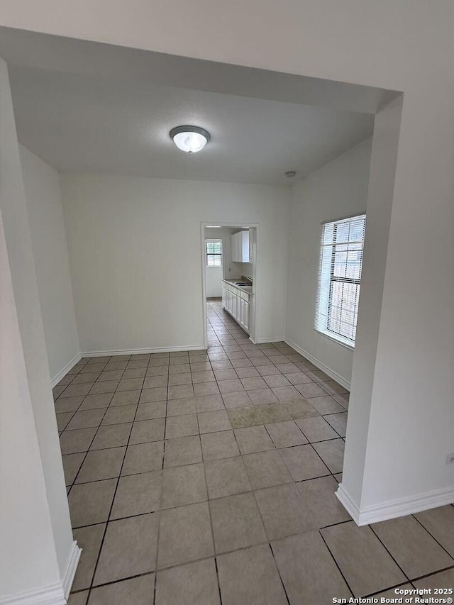 spare room featuring baseboards and light tile patterned flooring