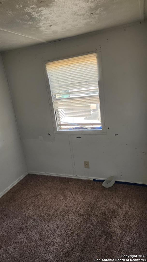 carpeted empty room with a textured ceiling and baseboards
