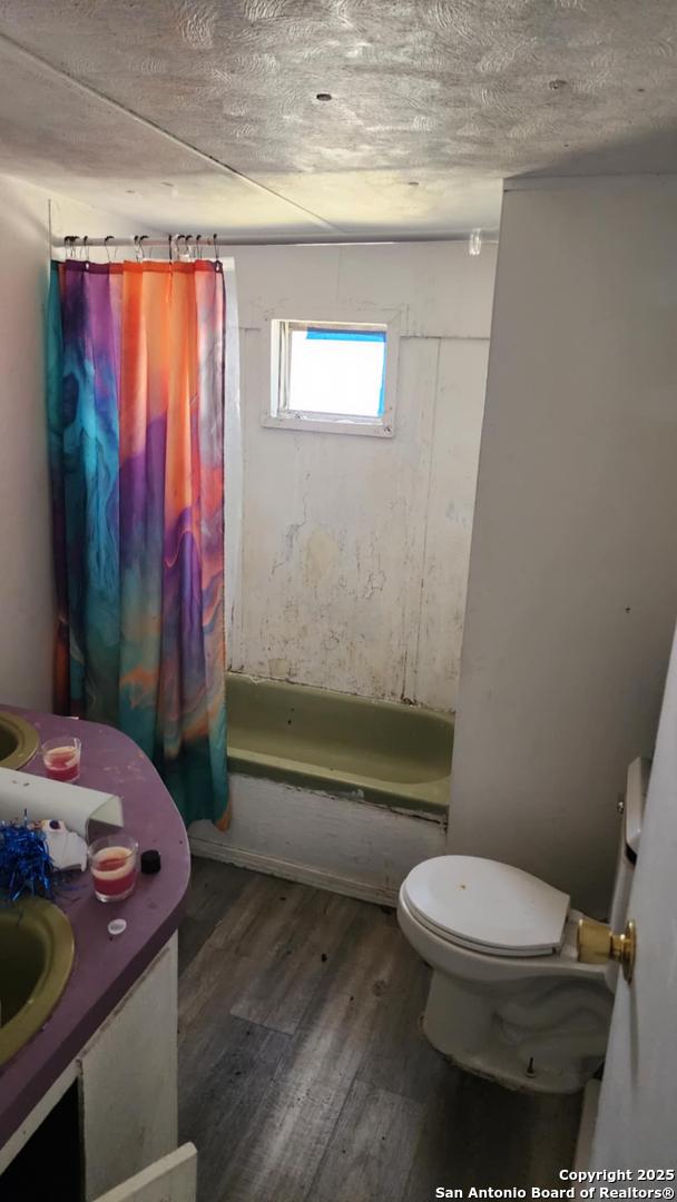 full bath with toilet, vanity, shower / bath combination with curtain, and wood finished floors