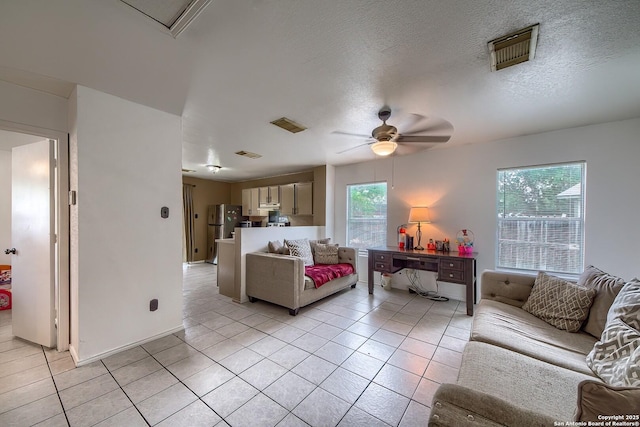 living room with light tile patterned floors, a textured ceiling, ceiling fan, and visible vents