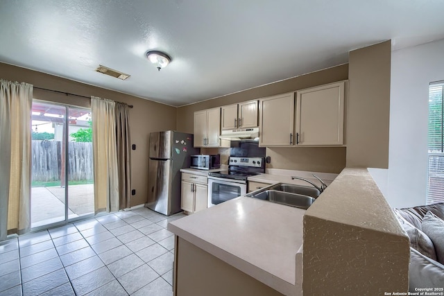 kitchen featuring a sink, stainless steel appliances, under cabinet range hood, visible vents, and light countertops