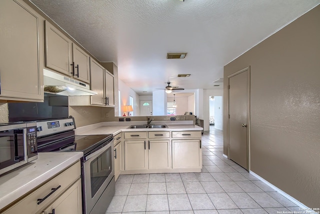 kitchen with light tile patterned floors, a sink, stainless steel appliances, under cabinet range hood, and a peninsula