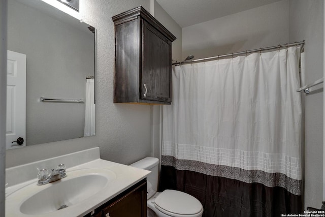 bathroom featuring toilet, a shower with curtain, a textured wall, and vanity