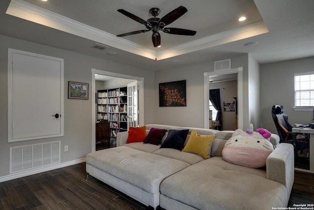 living area with visible vents, crown molding, a tray ceiling, and dark wood-style floors